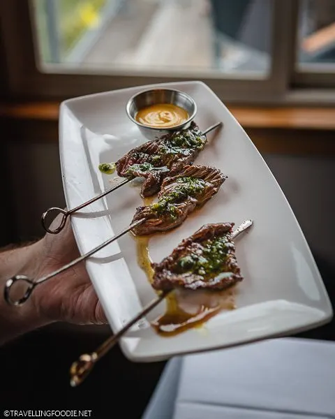 Holding Plate of Bison on Stick at Aurum Food and Wine