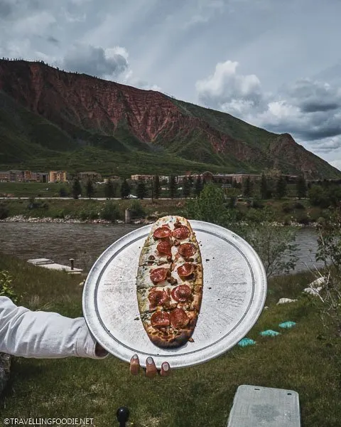 Lady holding Meat Lovers Pizza at Iron Mountain Hot Springs