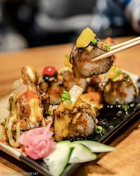 Lifting a piece of Aburi Salmon Maki with chopsticks