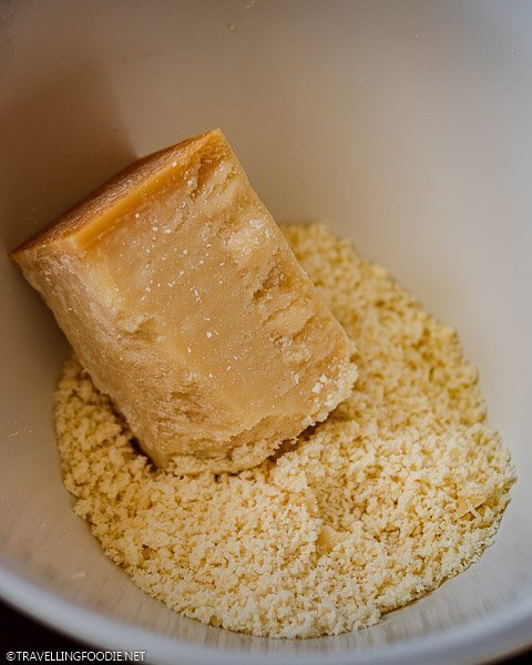 Block of Grana Padano Cheese on top of grated cheese
