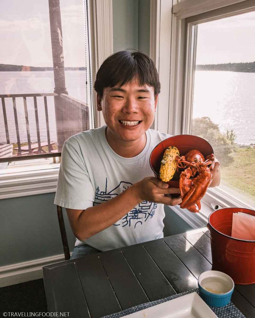 Travelling Foodie Raymond Cua holding bucket with lobster and corn at Argyler Restaurant in Argyle, Nova Scotia