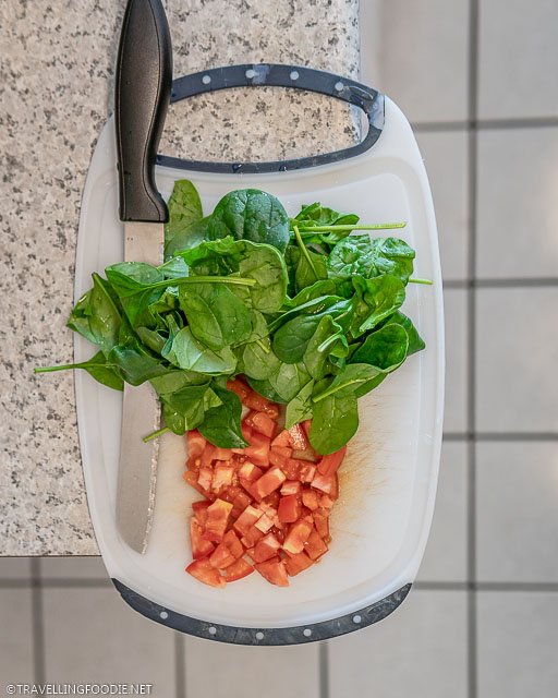 Tomatoes and Spinach with knife on a chopping board
