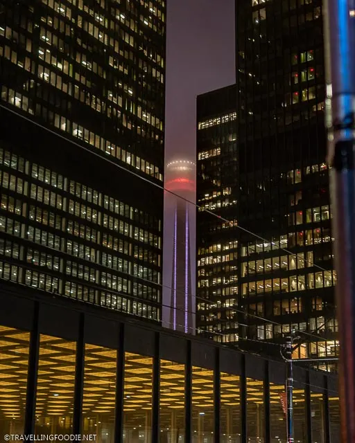 CN Tower framed by TD Buildings with yellow lights at night