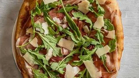 Whole Prosciutto and Arugula Cheese Italian Pizza on a Plate