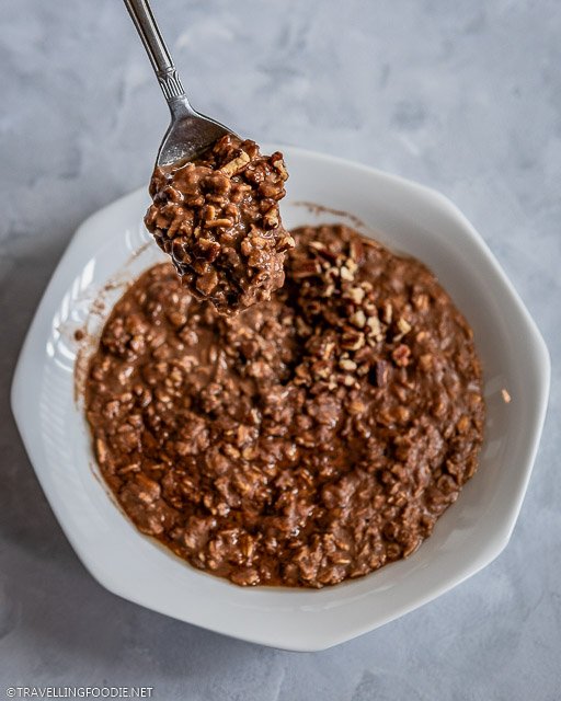 A spoon of chocolate oatmeal with crushed pecans