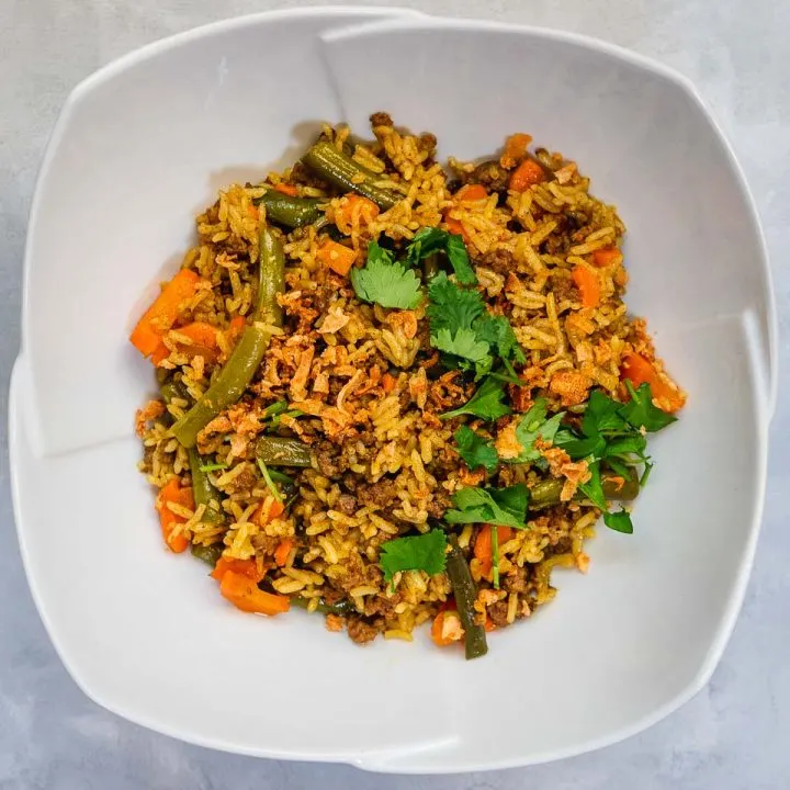 Instant Pot Beef Biryani on white bowl garnished with cilantro and crispy shallots