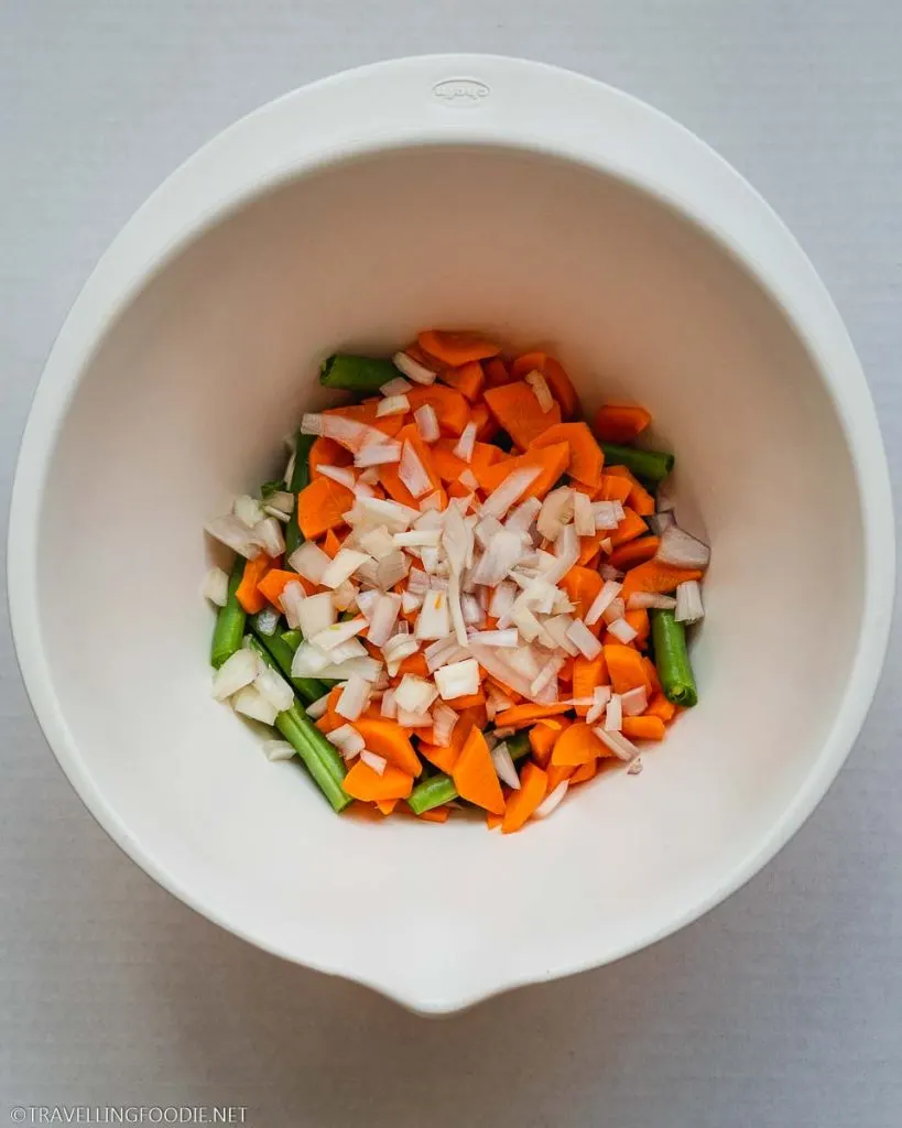 Green beans, chopped carrots and shallots on a bowl