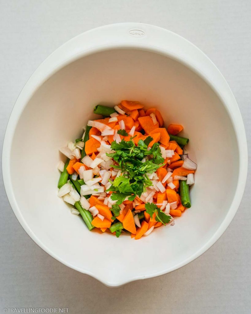 Cut green beans, chopped carrots, onions and cilantro on a bowl