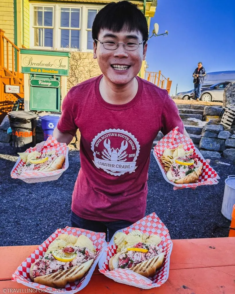 Travelling Foodie Raymond Cua with four lobster rolls at Breakwater Inn in Peggy's Cove, Nova Scotia