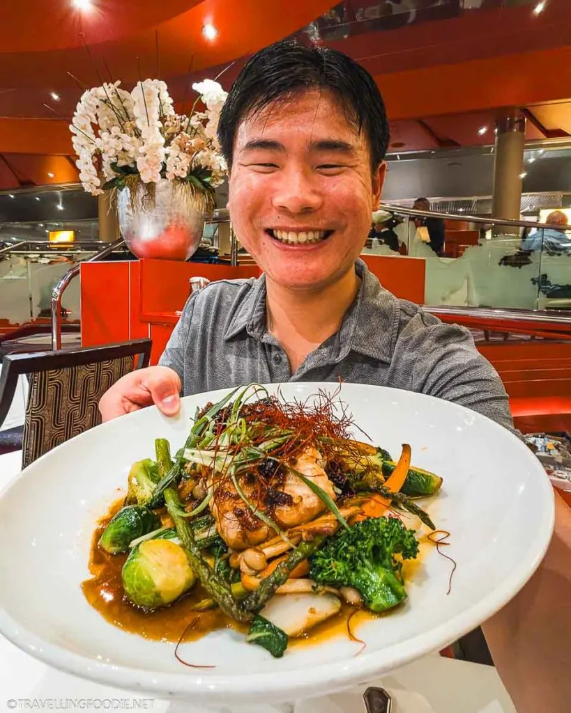 Travelling Foodie Raymond Cua holding a plate of Fish in XO Sauce at Holland America Nieuw Amsterdam MDR