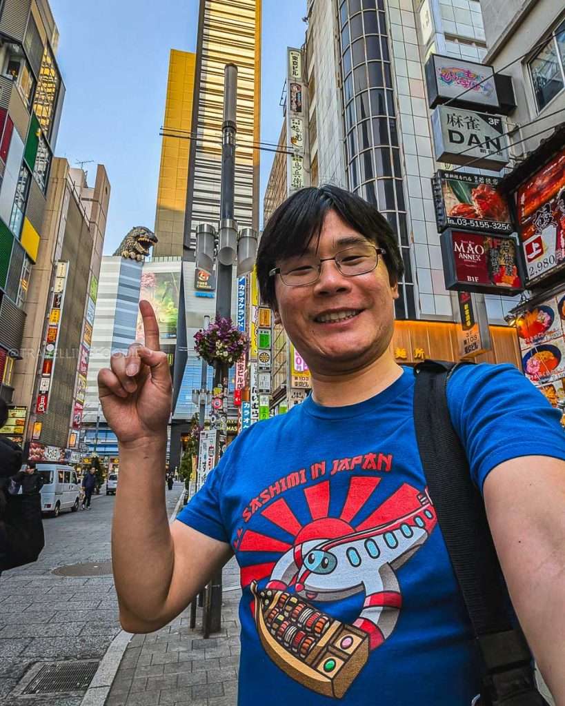 Travelling Foodie Raymond Cua pointing at Godzilla Head at Godzilla Road