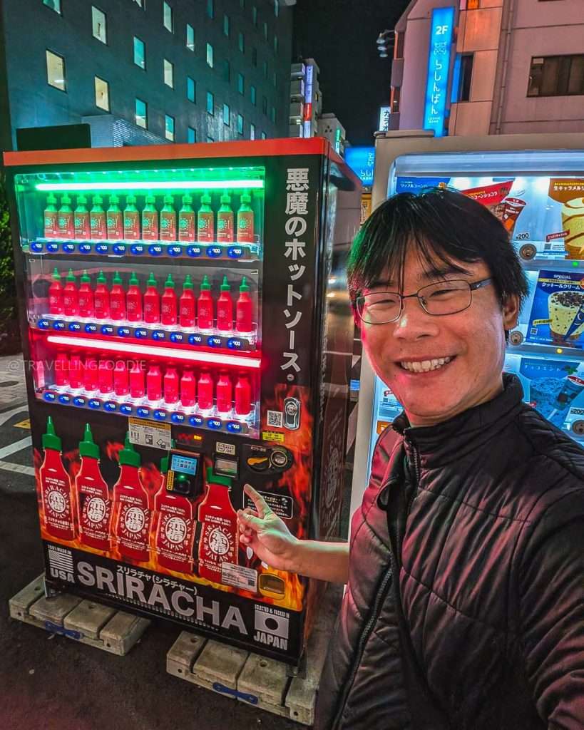 Travelling Foodie Raymond Cua pointing at Sriracha vending machine at Ikebukuro