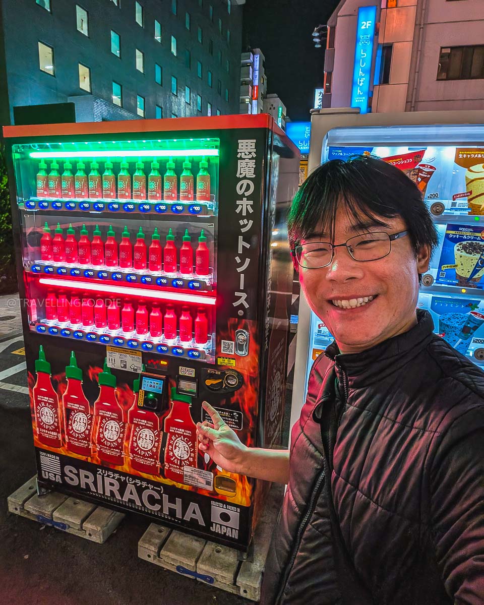 Travelling Foodie Raymond Cua pointing at Sriracha vending machine at Ikebukuro