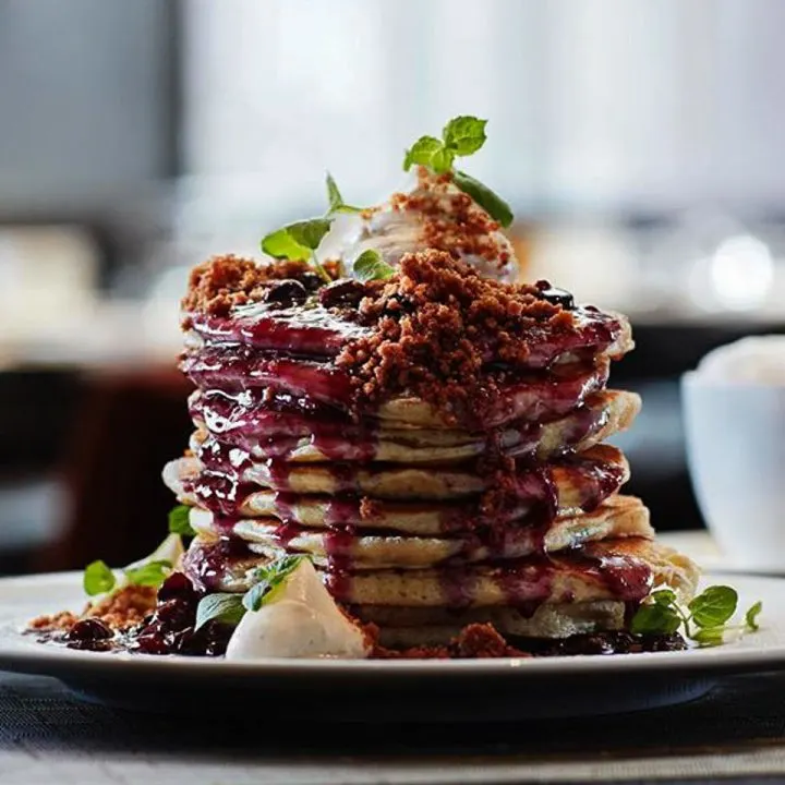 Stack of fluffy Blueberry Buttermilk Pancakes from ONE Restaurant topped with blueberry compote and vanilla cream cheese.