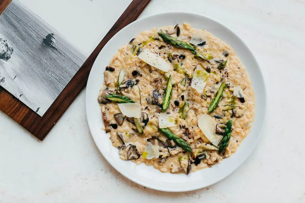 Overhead shot of creamy Wild Mushroom Risotto in a bowl topped with shaved parmesan and truffle oil at Ricarda's Restaurant.