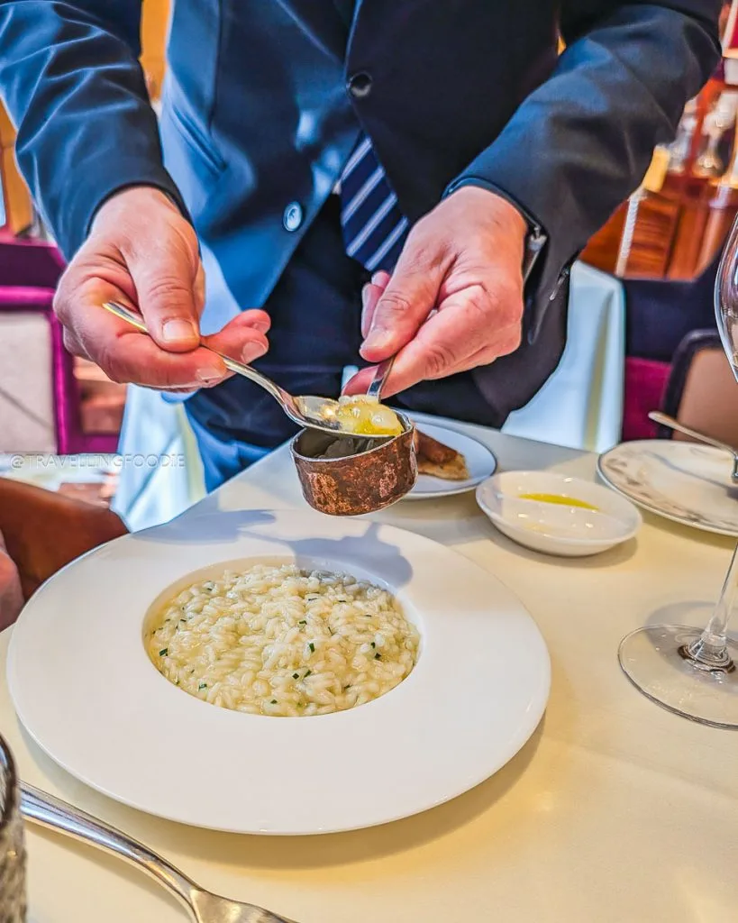 Waiter serving sauce over brown butter risotto at fine dining Ristorante Acanto Milan.