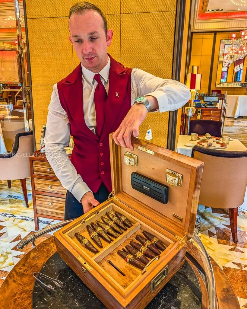 Waiter presenting a wooden box of chocolate cigars for dessert at Ristorante Acanto Milan.