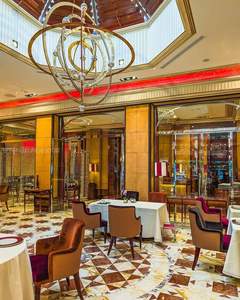 Elegant dining room of Ristorante Acanto featuring Murano chandeliers and marble floors.
