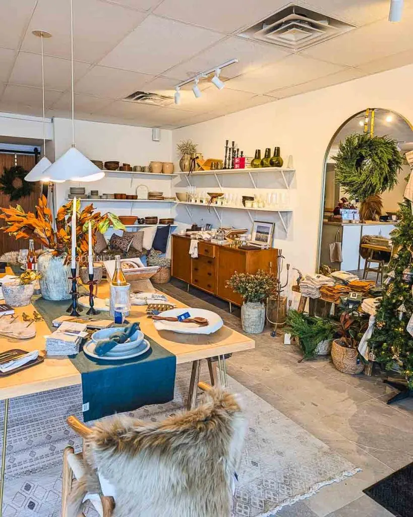 Modern rustic interior of Juniper, the retail store of The Pine, featuring wooden tables, pottery shelves, and holiday decor