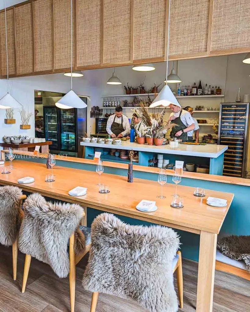 Chef's Counter at The Pine Creemore featuring fur-covered chairs and an open kitchen view of chefs preparing the tasting menu.