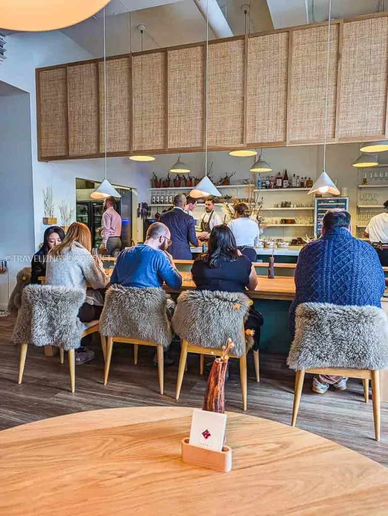 Busy dining room at The Pine Creemore with guests at the Chef's Counter watching Michelin Star chefs in the open kitchen.