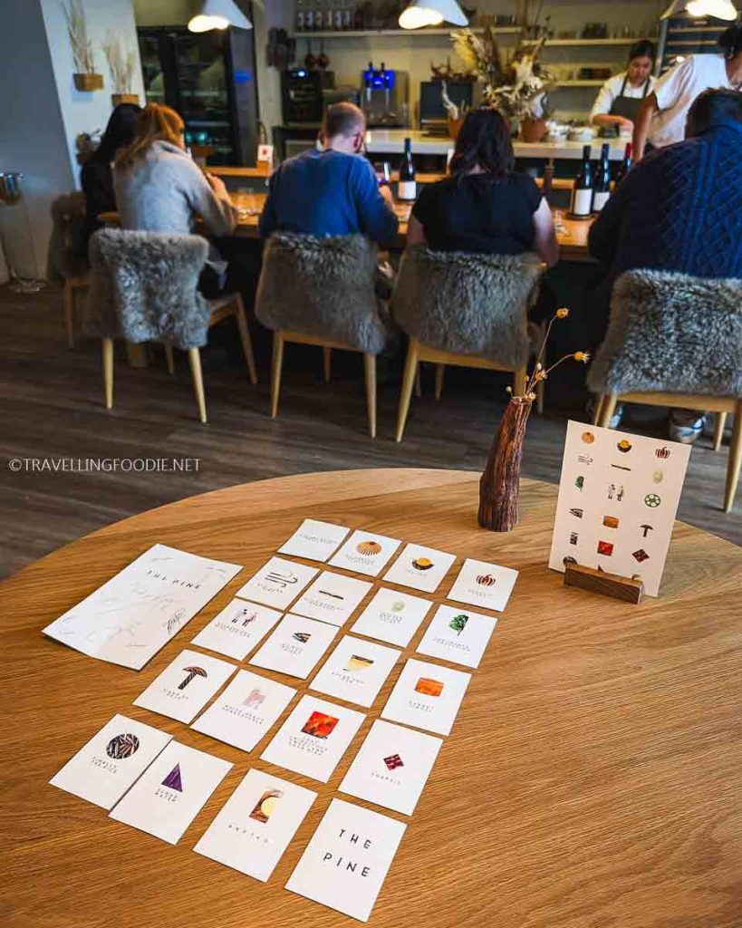 Interior of The Pine Creemore dining room with menu cards on table and view of Michelin Star open kitchen.
