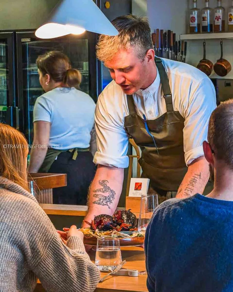 Chef serving the Charsiu Squab course at The Pine Creemore Michelin Star restaurant table.