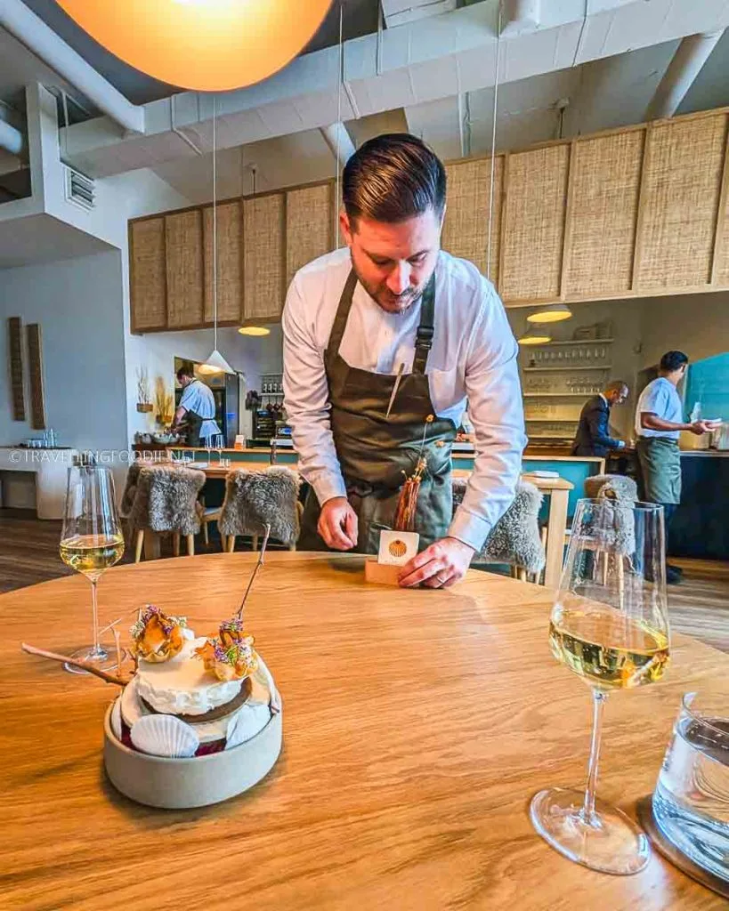 Chef Jeremy Austin serving a course paired with champagne at The Pine Creemore, a Michelin Star dining experience in Ontario.