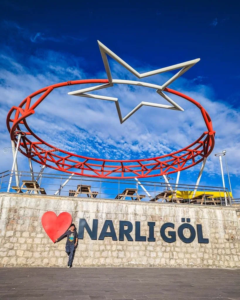 Raymond Cua posing with the Narligol sign and heart sculpture at the Nar Crater Lake stop