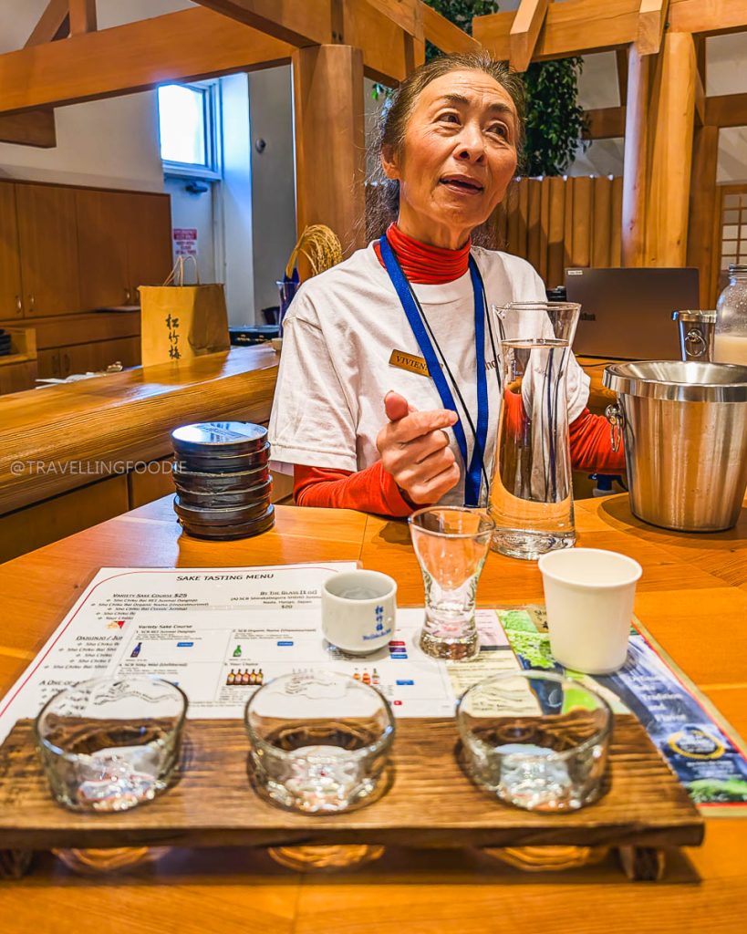 Sake guide Vivienne pouring a tasting flight at Takara Sake USA, highlighting unique specialty food and drinks in Berkeley.