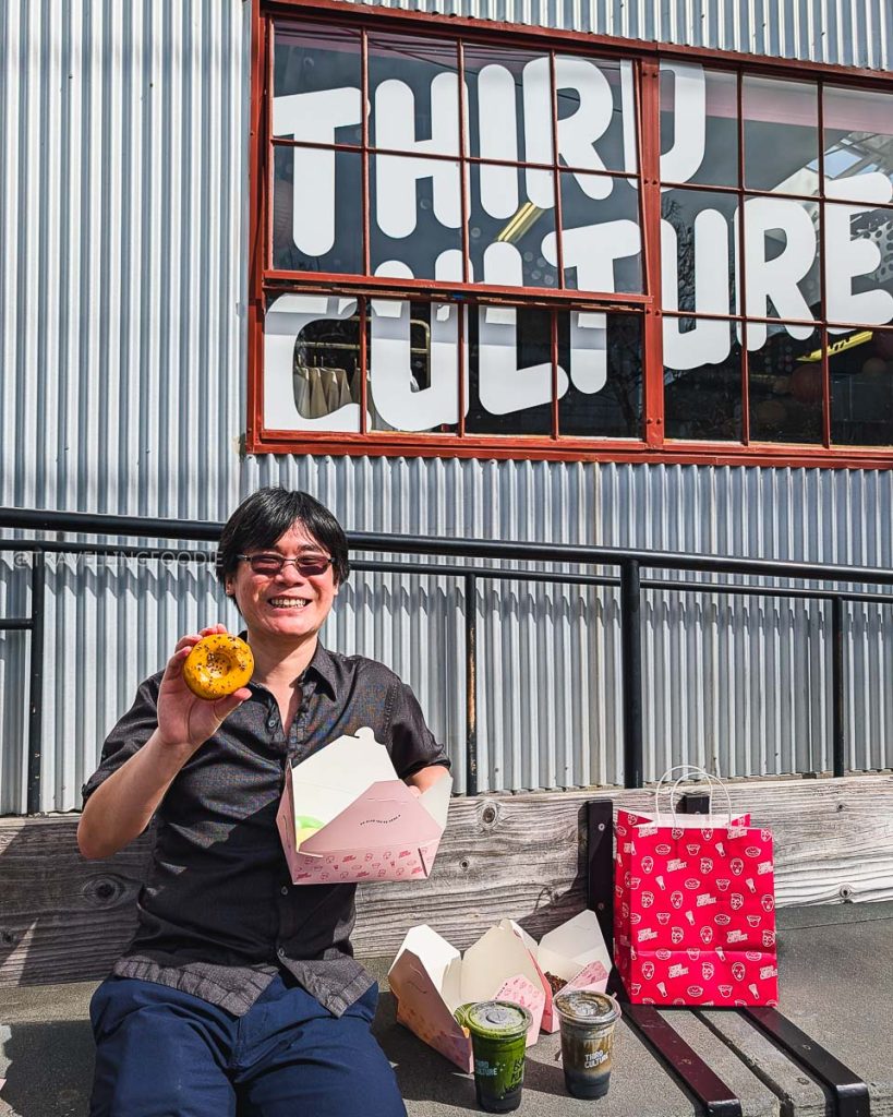 Travelling Foodie Raymond Cua enjoying a famous butter mochi donut outside Third Culture Bakery, a top place to eat in Berkeley.