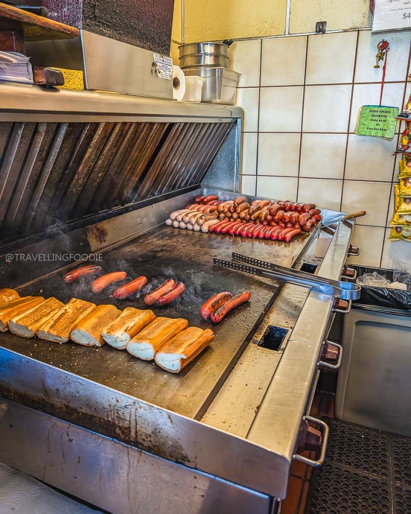 Sizzling sausages and toasted buns on the grill at Top Dog, a legendary institution for places to eat in Berkeley.