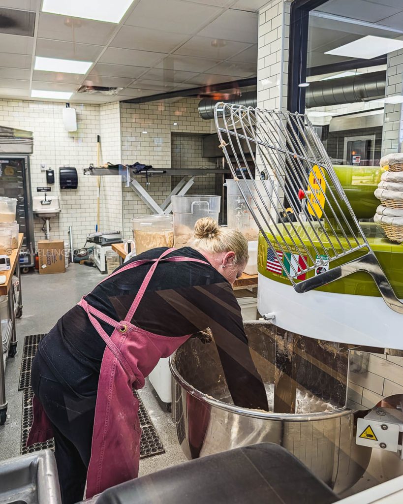 Baker making fresh sourdough in a mixer at Alibi Wood Fire Pizzeria, a top place to eat in Laramie for artisan food.