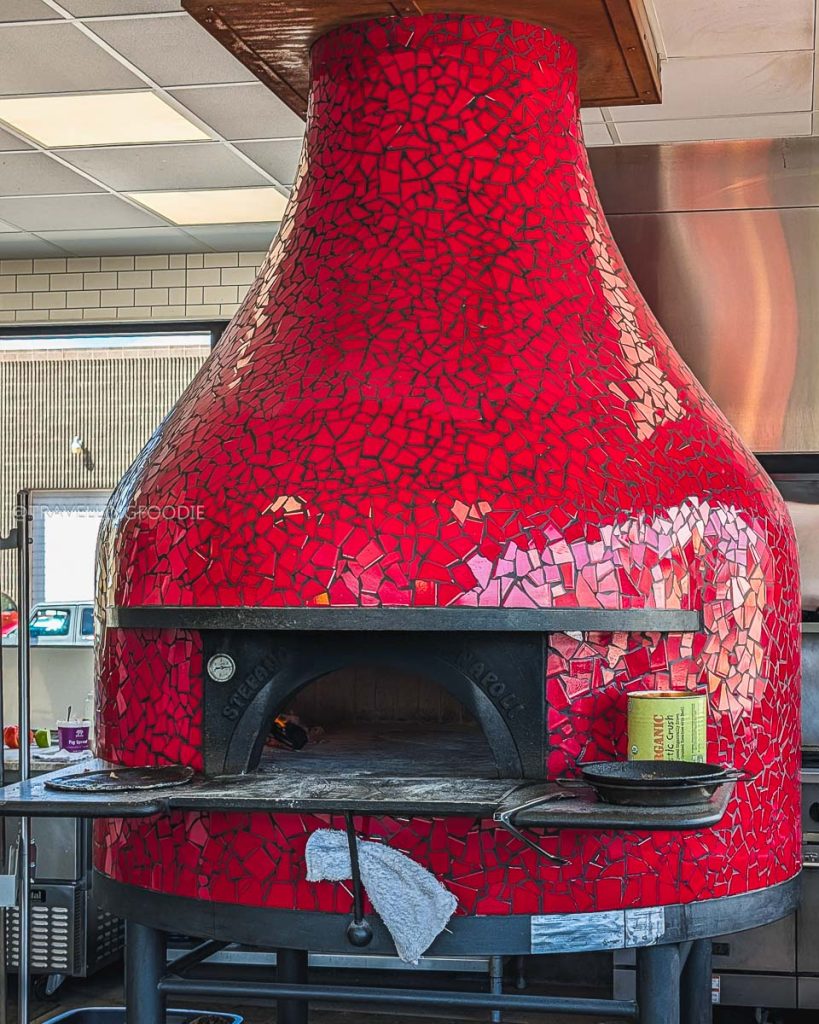 Close up of the red mosaic wood-fired oven baking authentic pizzas for the vibrant Laramie food scene at Alibi.
