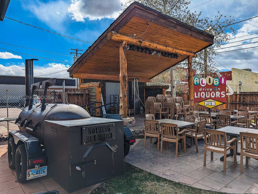 Outdoor smoker and covered patio seating at Alibi Wood Fire Pizzeria, offering some of the best Laramie food.