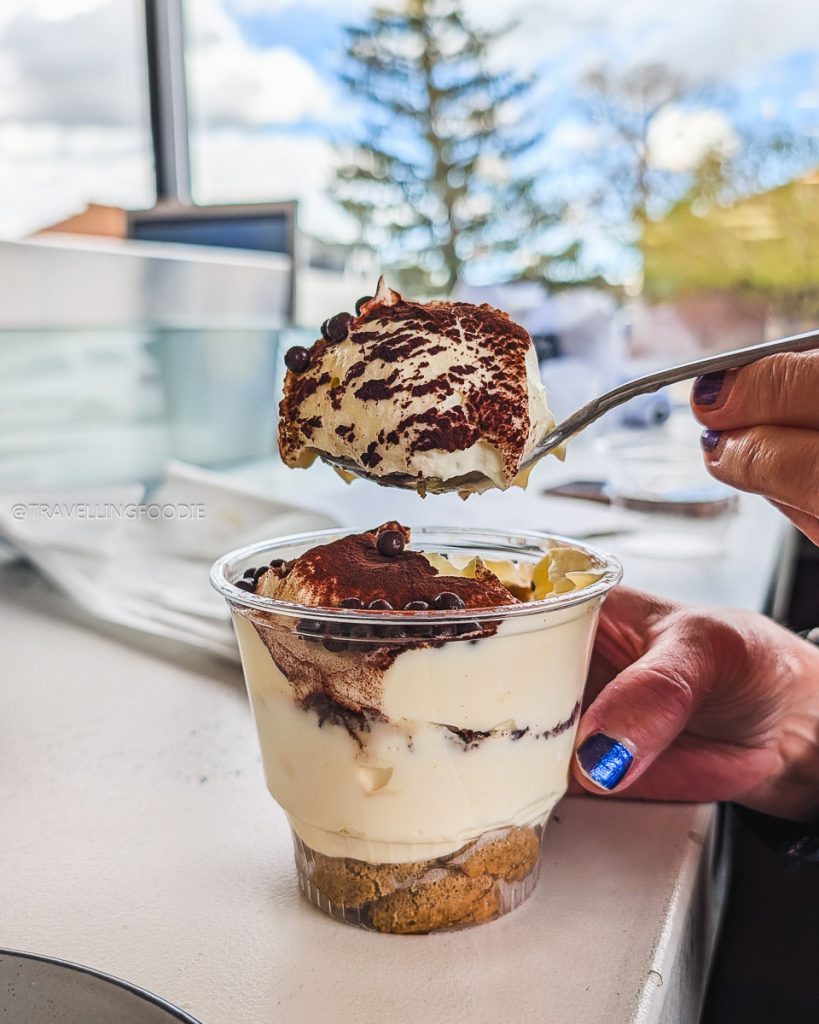 A spoonful of rich, creamy tiramisu dessert at Alibi Wood Fire Pizzeria, a sweet highlight of the Laramie food scene.