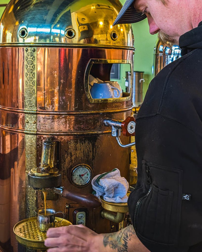 Barista pulling an espresso shot from a vintage copper machine at a cozy Laramie cafe for a Laramie breakfast.