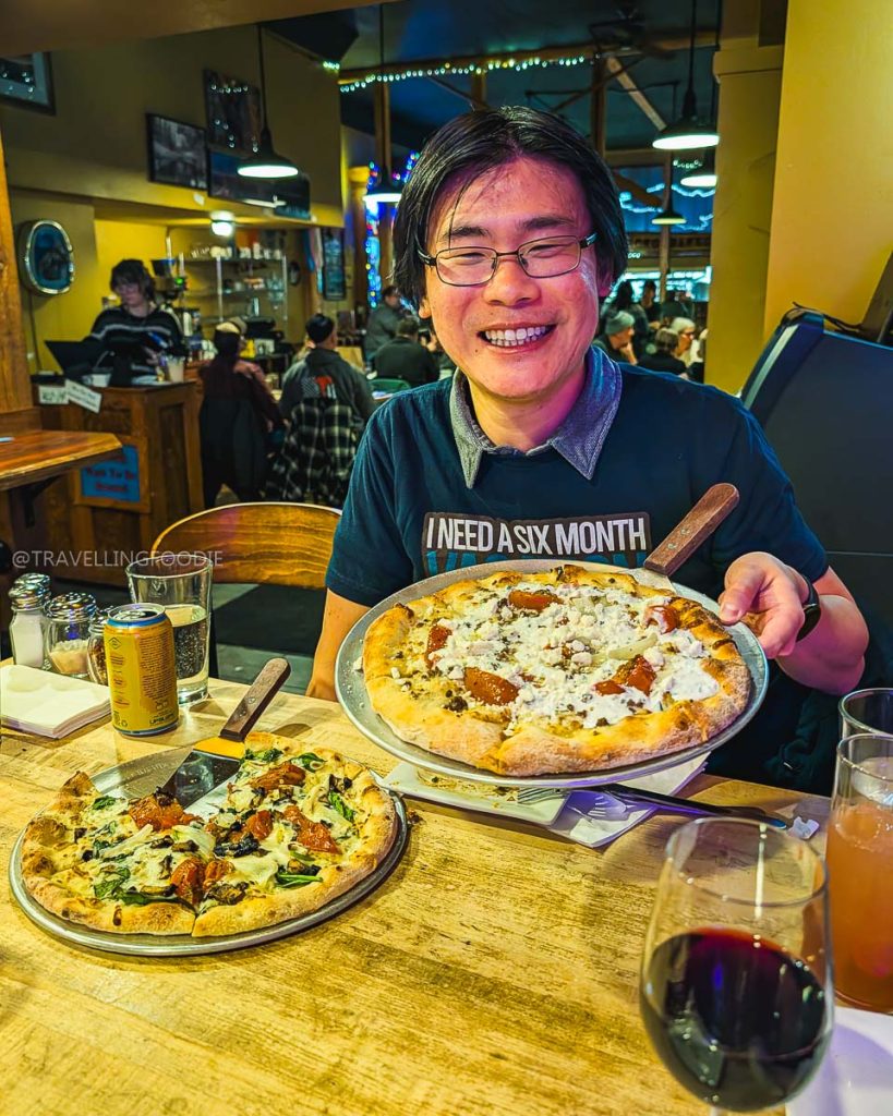Travelling Foodie holding the Billhook Pizza at The Crowbar and Grille, a top choice for places to eat in Laramie.