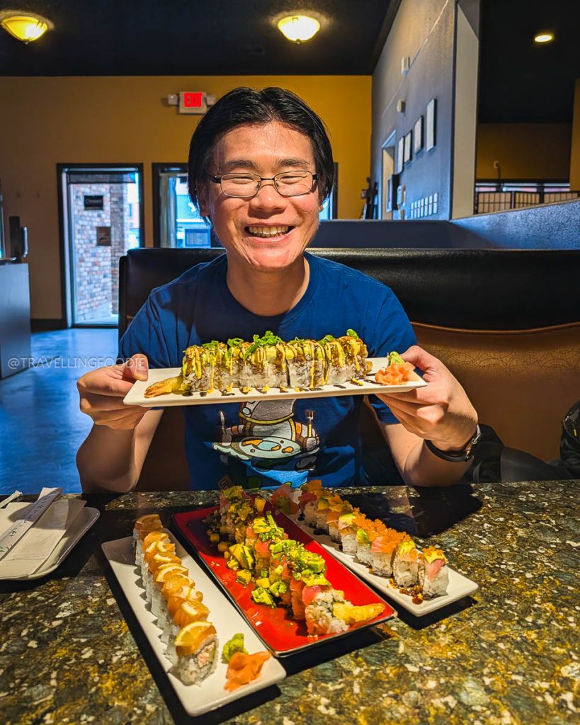 Travelling Foodie holding a platter of rolls at Mizu Sushi, highlighting authentic places to eat in Laramie.