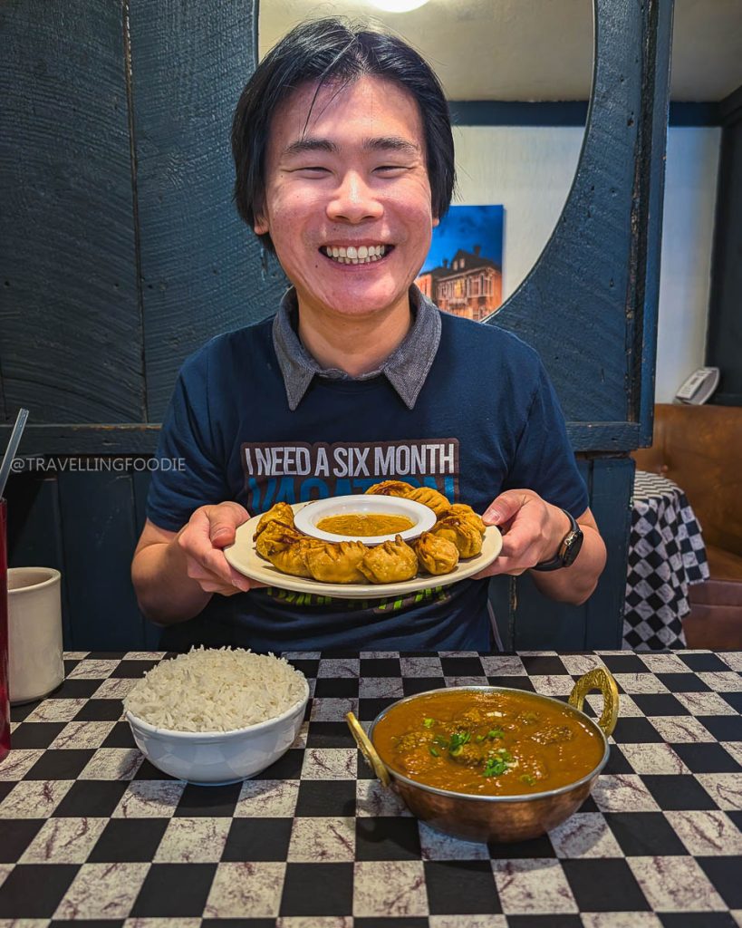 Travelling Foodie holding crispy momos at Momo House which is one of the best restaurants in Laramie.