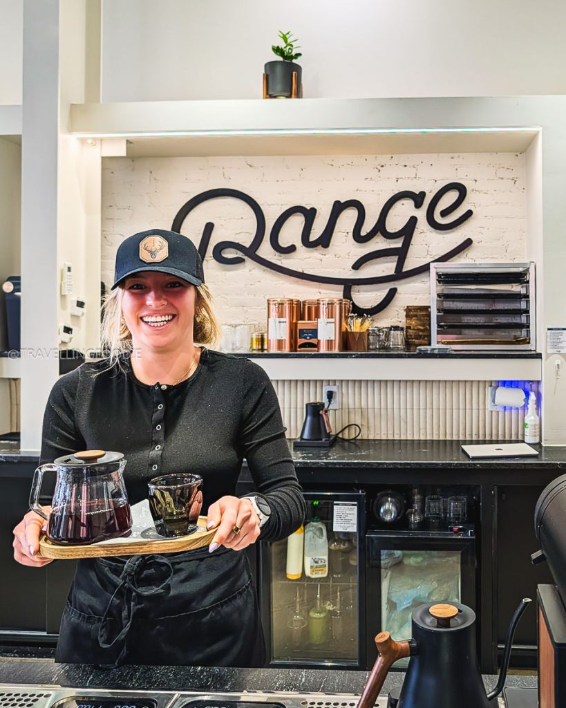 Barista serving a fresh pour over coffee at Range Coffee Roasters a top choice for Laramie cafes.