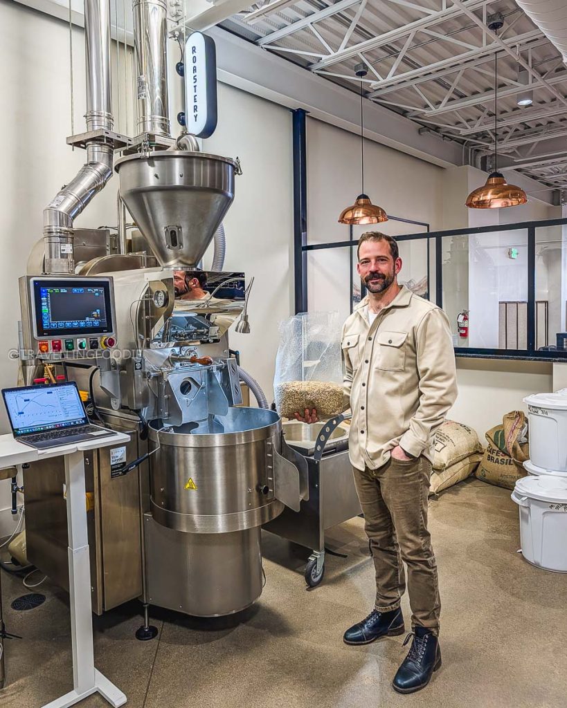 Kyle Koster standing by the Loring roaster at Range Coffee Roasters a top spot for the Laramie drink scene.