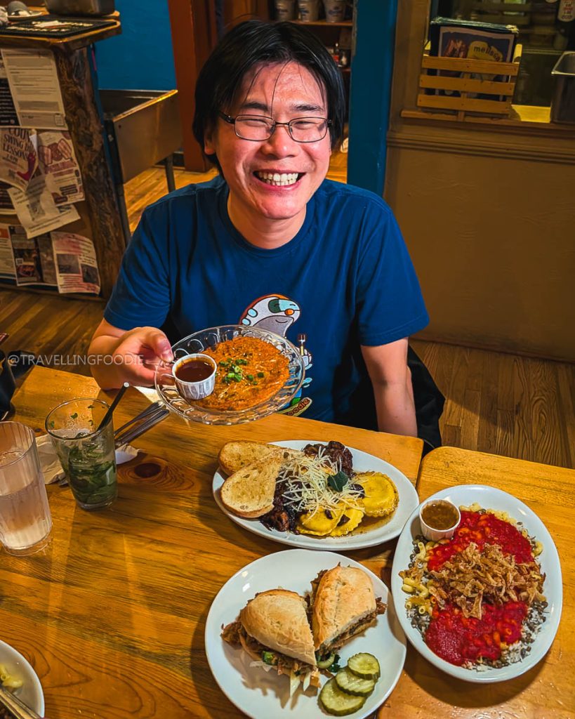 Travelling Foodie Raymond Cua holding Kimchi Pancake dish at Sweet Melissa Cafe while exploring the best places to eat in Laramie.