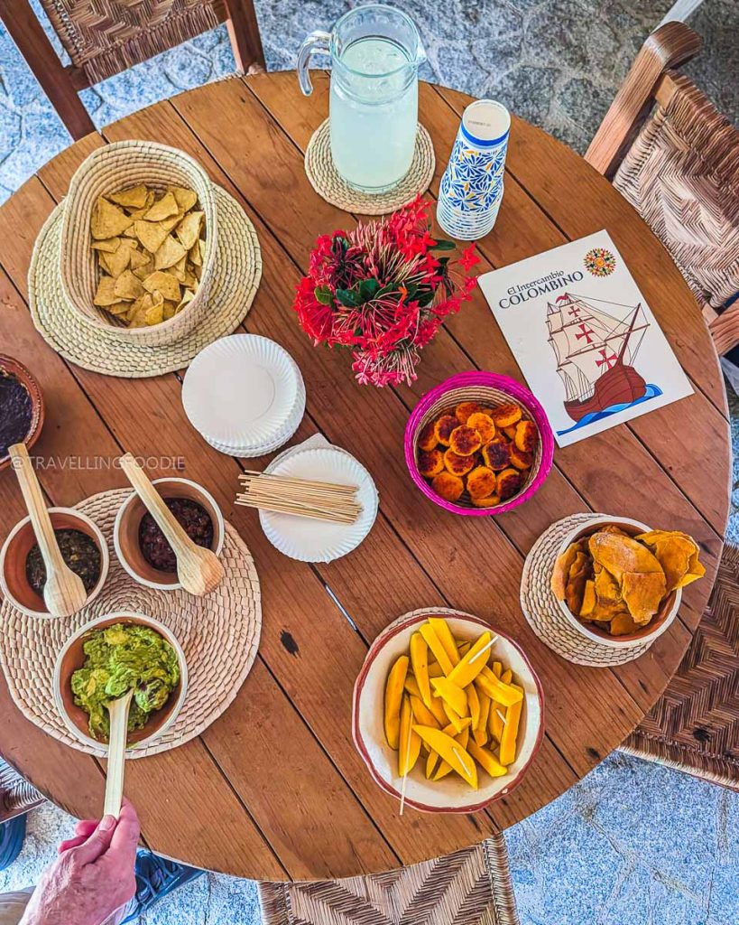 Wooden table filled with delicious local Acapulco food like guacamole, tortilla chips, and fresh mango slices.