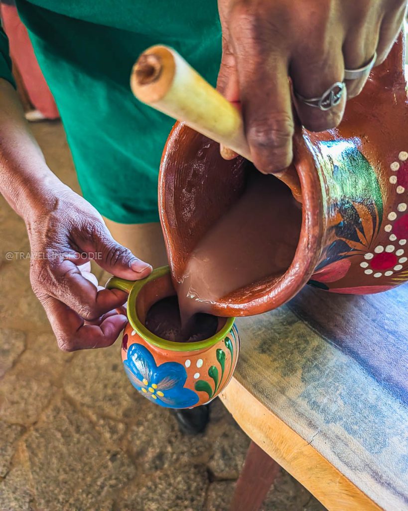 Pouring traditional chilate drink from a beautiful painted clay pitcher into a colorful cup at Acapulco Botanical Garden