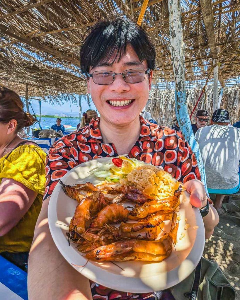 Travelling Foodie Raymond Cua holding a plate of amazing grilled shrimp at a Barra de Coyuca beach shack.