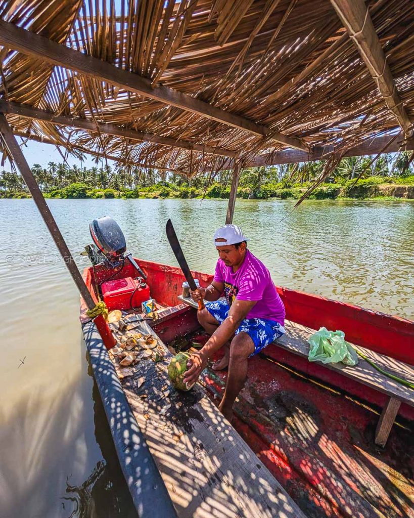 Local guide preparing fresh coconuts on a boat at Coyuca Lagoon, a must do in Acapulco for nature lovers.