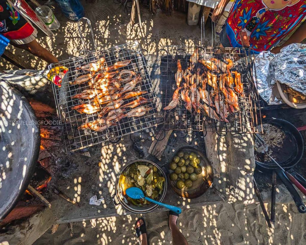 Overhead view of fresh shrimp grilling over an open wood fire, highlighting amazing local food in Acapulco.
