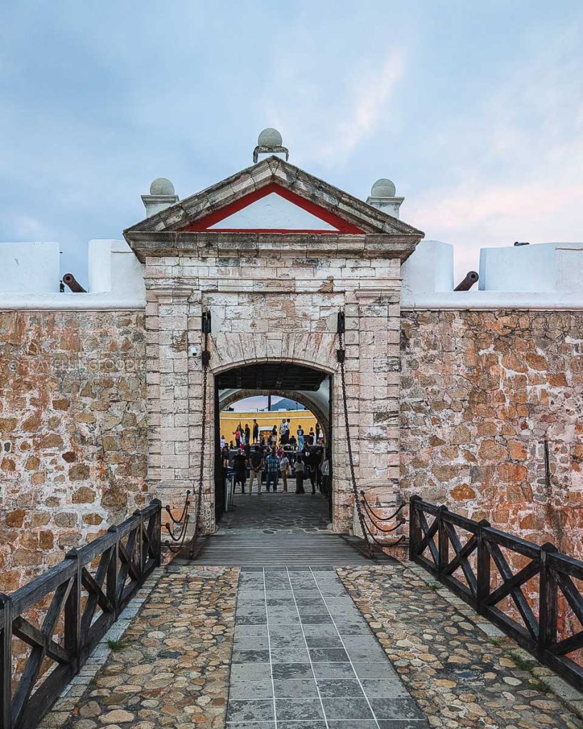 Stone entrance gate and wooden bridge leading into the Acapulco Historical Museum of Fort San Diego.
