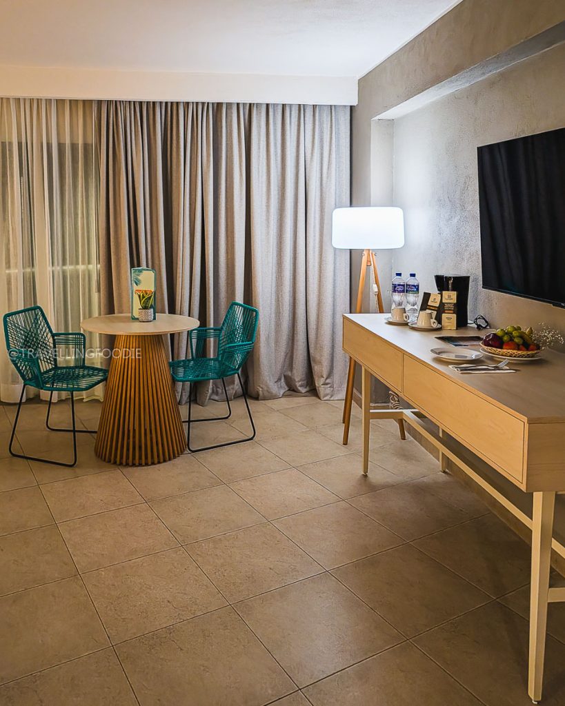 Interior of a Room Comfort at Hotel Amares in Acapulco, featuring a modern dining table, teal chairs, and amenities.